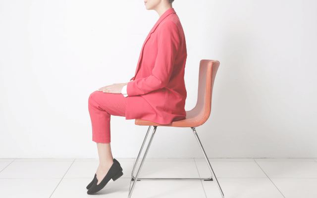 椅子に座ってかかとをあげている女性
